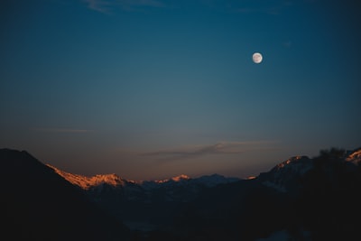 积雪盖顶的山脉在晚上时间与月球
